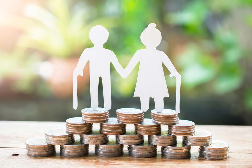 A cutout of an elderly couple on top of a stack of coins to symbolize a retirement fund.