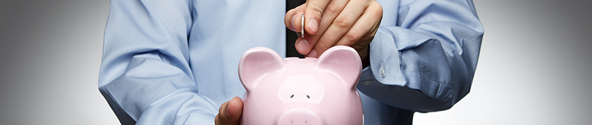 A businessman putting a coin into a piggy bank