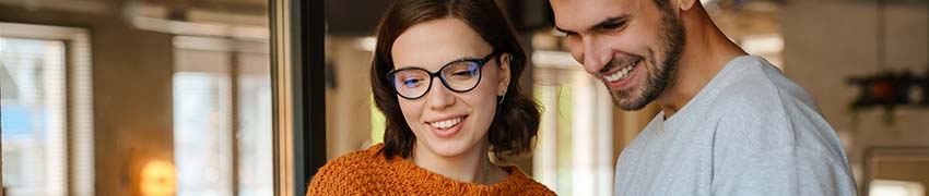 A young man and woman smiling while using a laptop to review finances