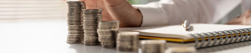 Rising stacks of coins next to a journal.