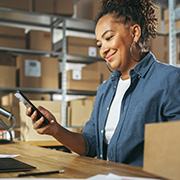 A woman smiling while using her phone in a storage facility.