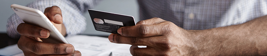 A man using his credit card and cellphone at a café