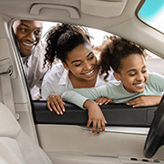 A happy family looking at the inside of a new car.