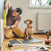 A man working on home repair with his dog.